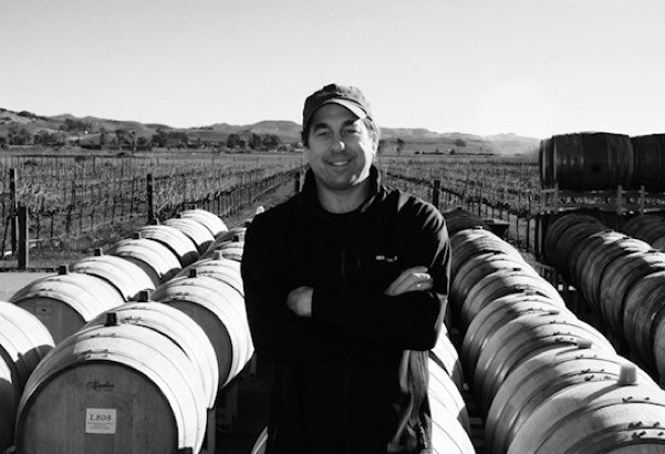 A man standing in front of wine barrels